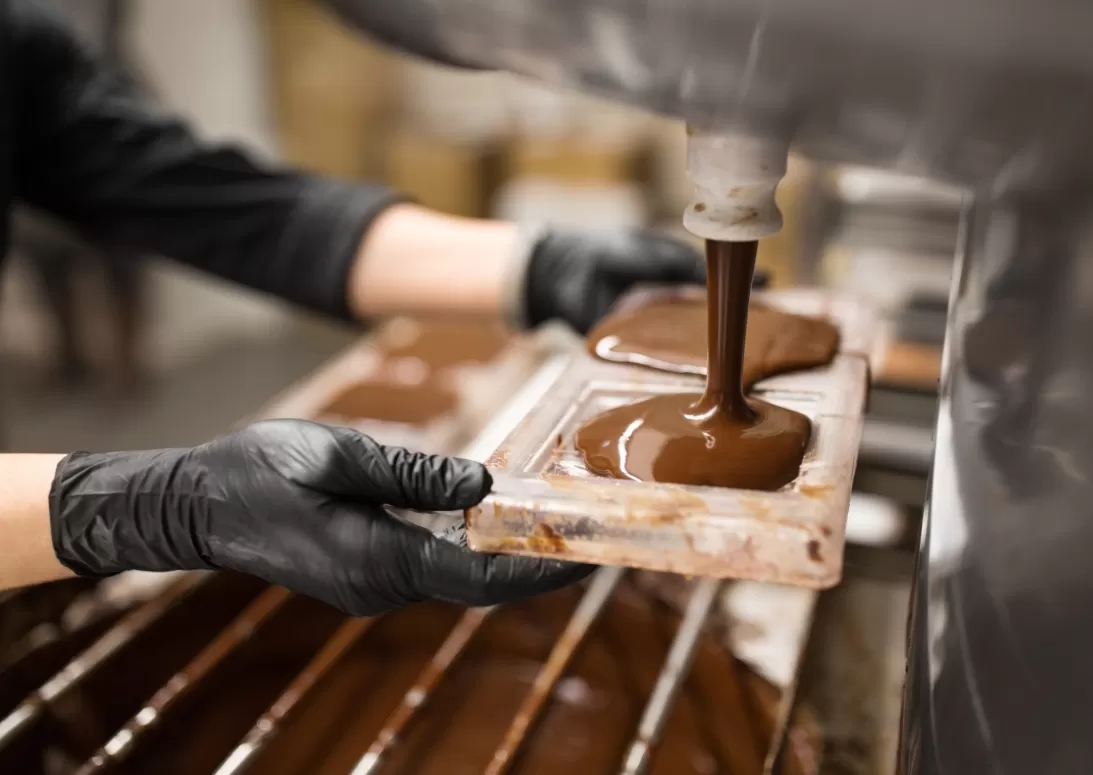 Worker filling molds with melted chocolate