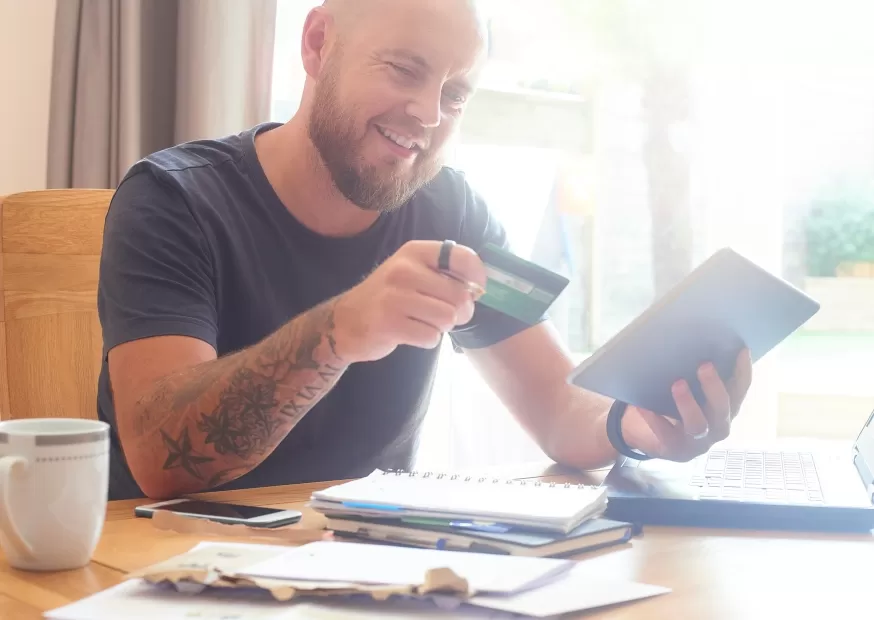 Tattooed man working on plan to save money and manage debt. 